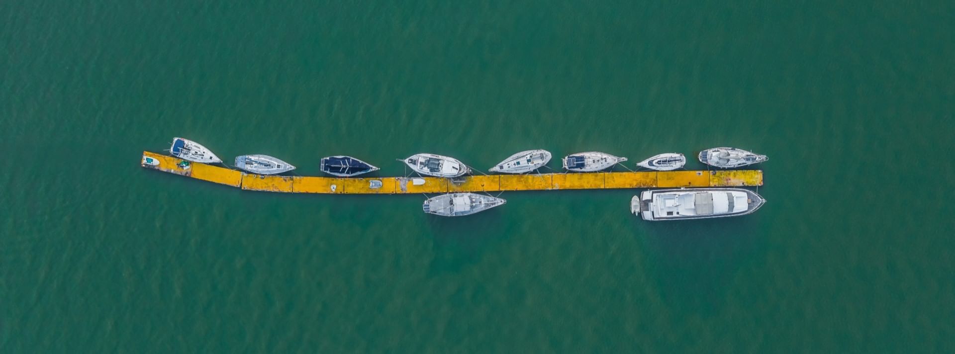 Aerial view of boats docked along a yellow pier on the sea near Sunway Hotel Big Box