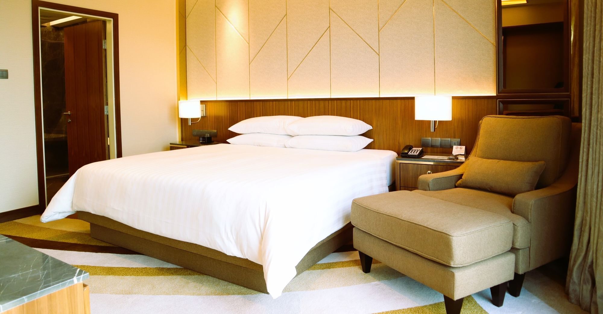 A serene hotel room with a neatly arranged bed, a comfortable chair at the Sunway Hotel Big Box
