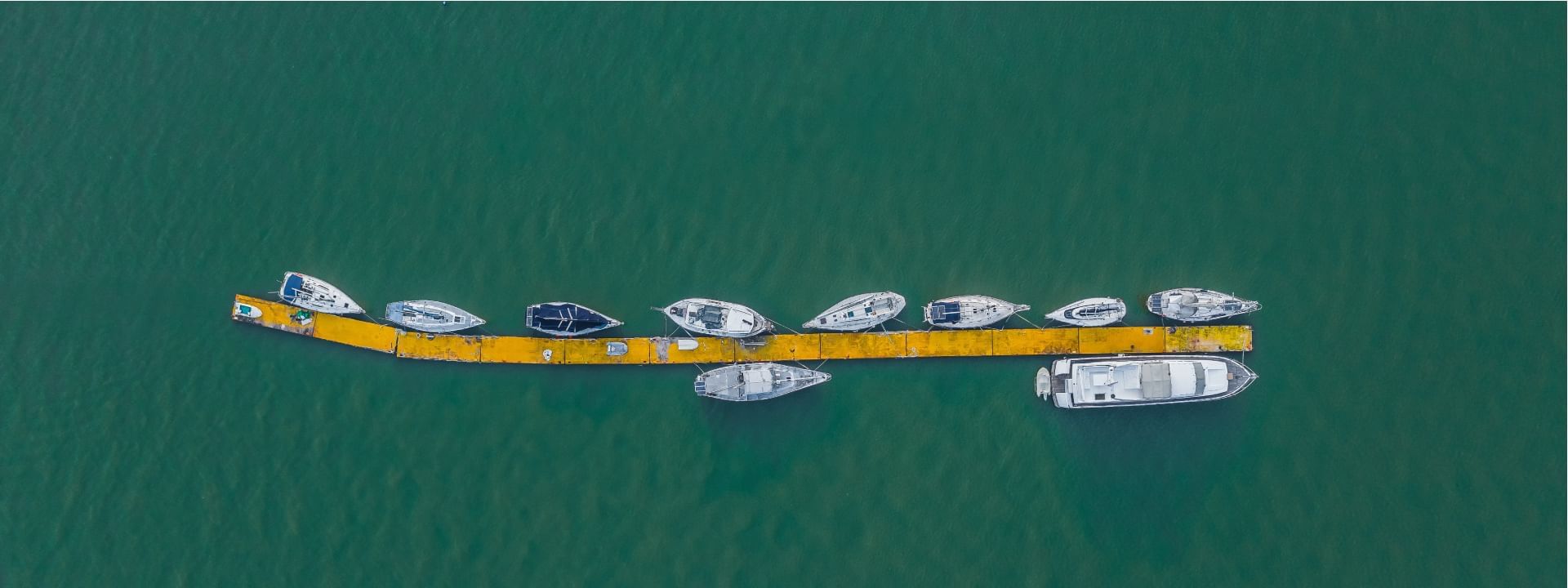 Aerial view of boats docked along a yellow pier on the sea near Sunway Hotel Big Box
