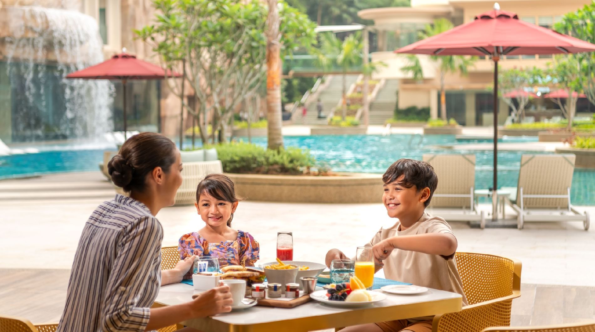 Family enjoying a sunny outdoor breakfast by the pool at Sunway Resort