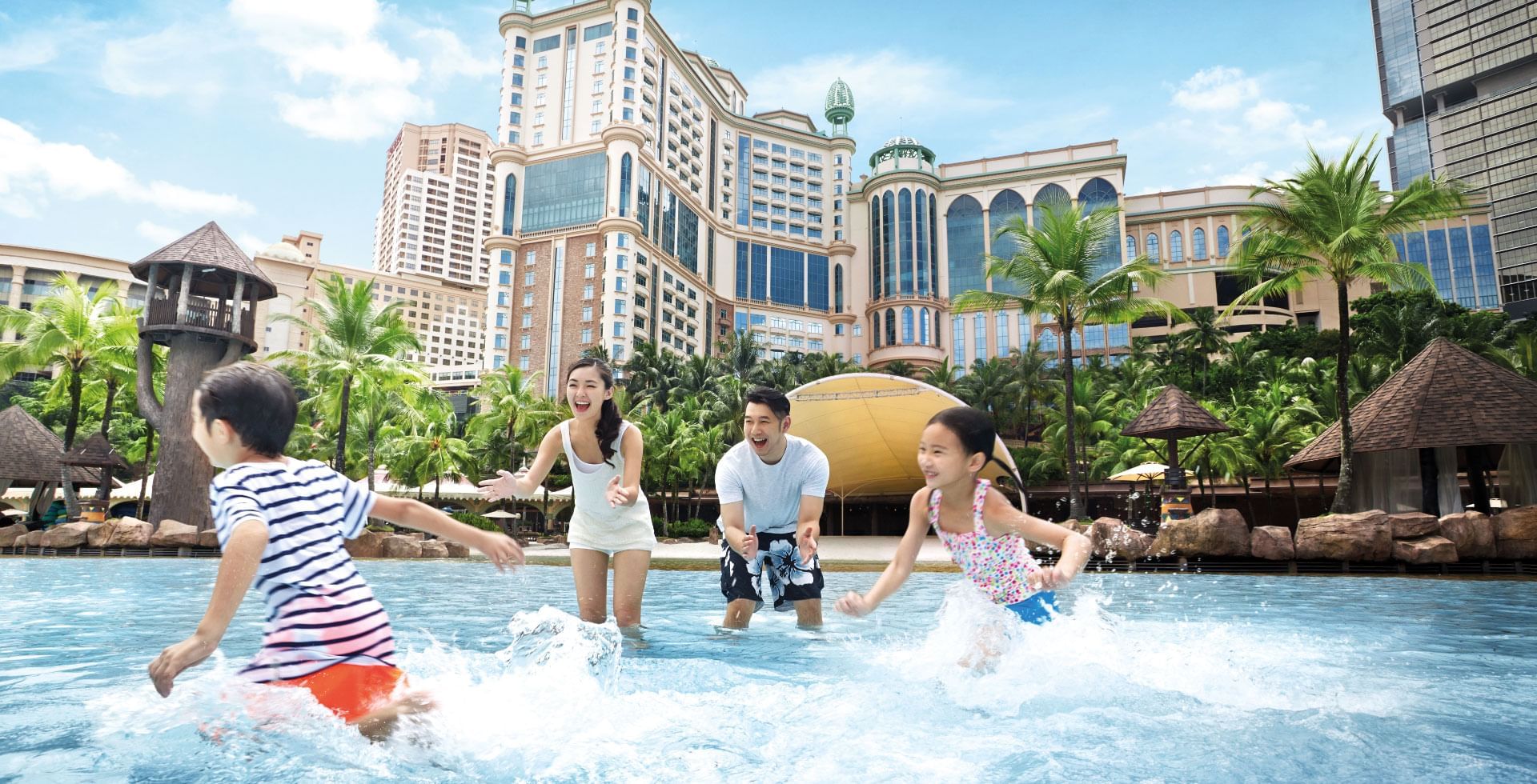 A joyful family splashing in the pool at Sunway Hotel Pyramid, with the impressive resort buildings in background