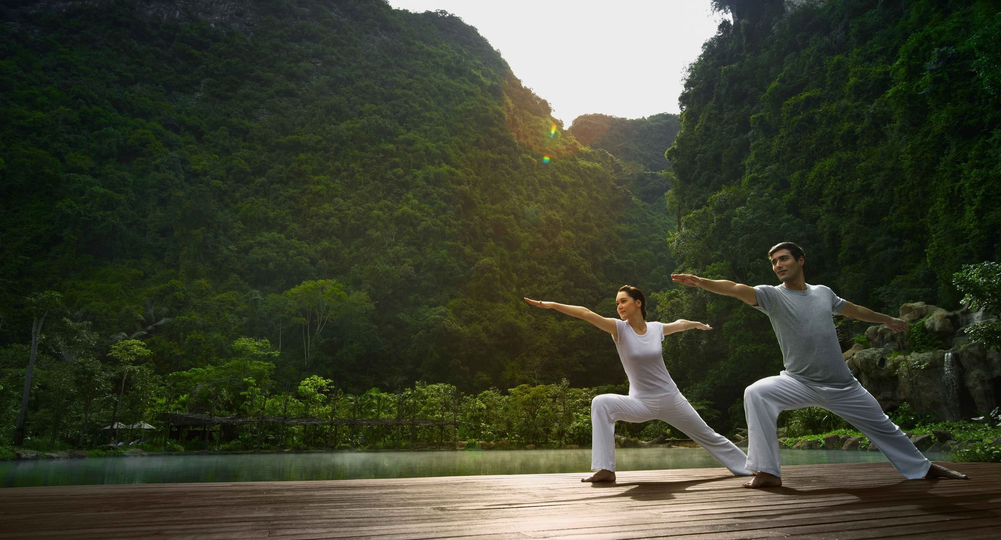 Couple doing yoga poses on the deck in Yoga class at The Banjaran Hotsprings Retreat